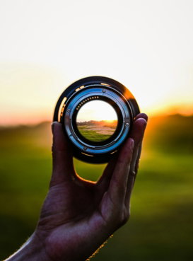 a person holding a camera lens in their hand